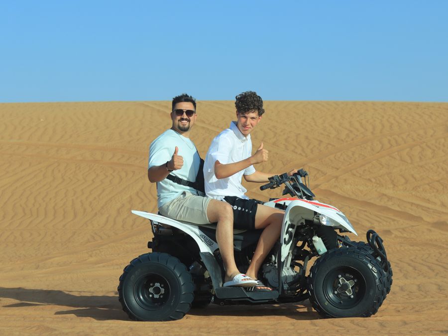 Deux amis souriants sur un quad dans le désert