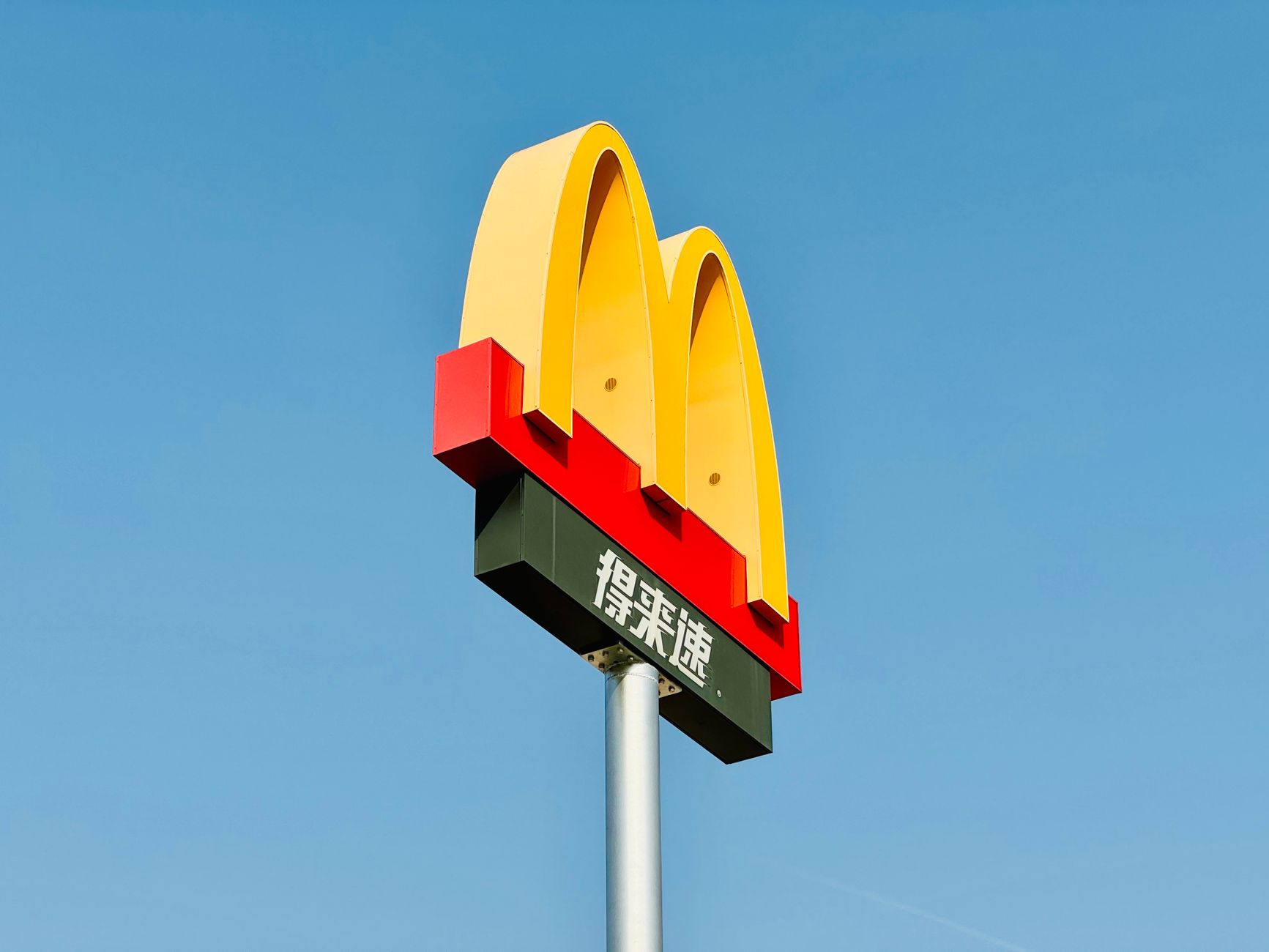 Iconic McDonald's sign soaring against a clear blue sky in Dong Li Qu, Tianjin, China.