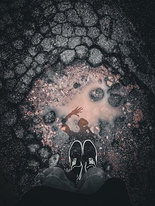 A person's feet are in the middle of a puddle