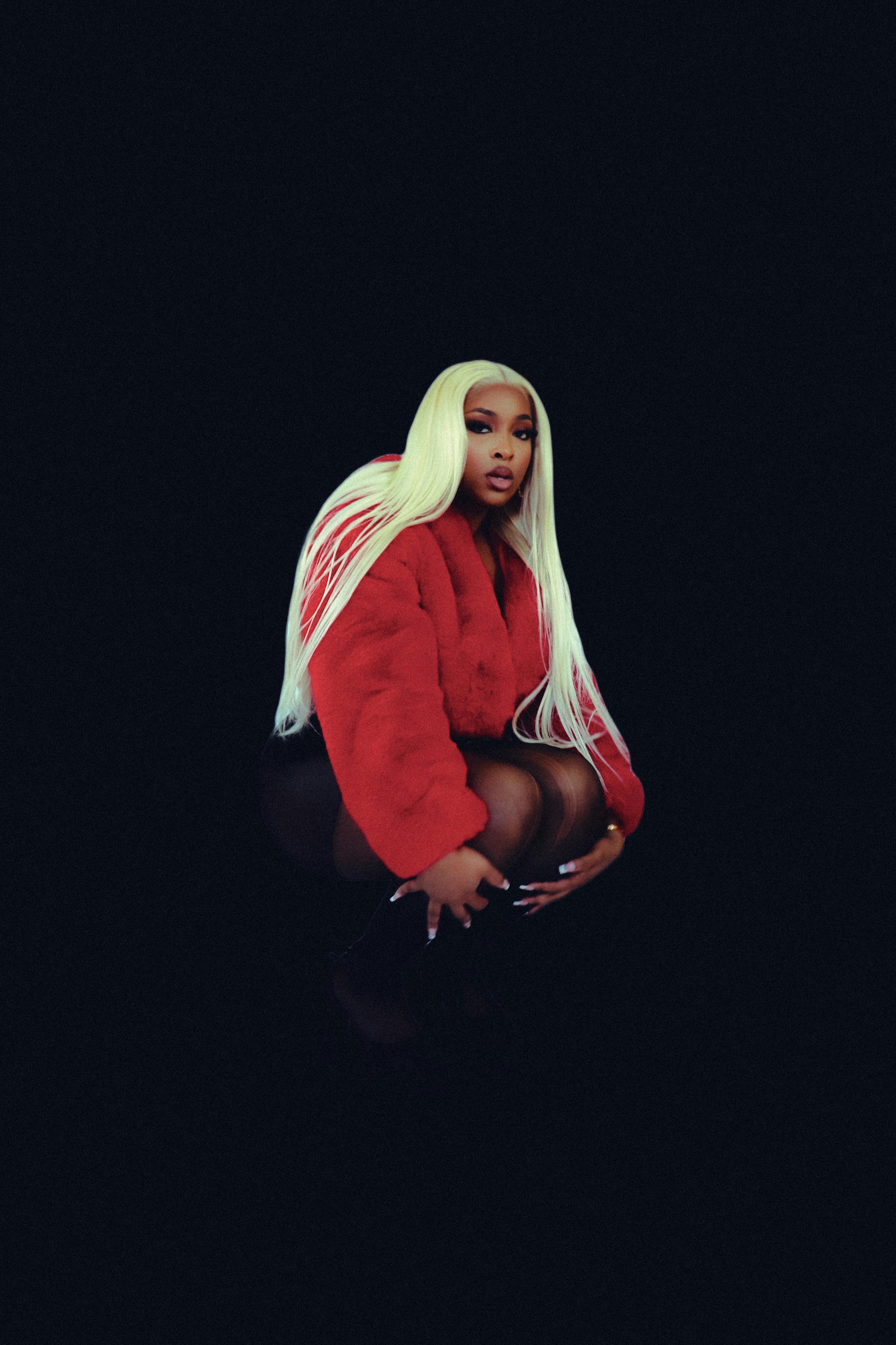 Fashion model posing in studio, wearing a red jacket and long blonde hair, stylish and elegant.