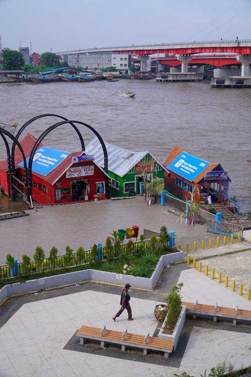 A man walks past a row of small houses on the river