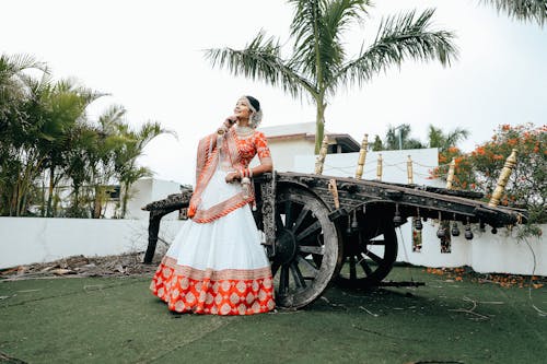 A woman in an orange and white lehenga poses for the camera