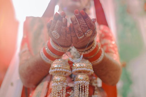 A bride in traditional indian attire with her hands up