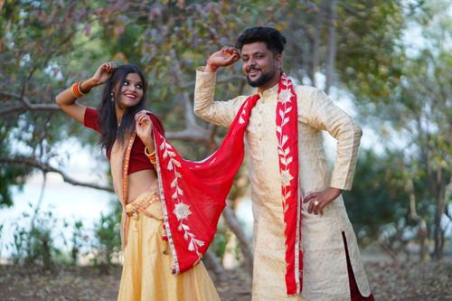 Free A couple joyfully dancing in traditional Indian clothing with vibrant red scarves outdoors. Stock Photo