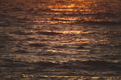 Free A serene view of sunset light reflecting on ocean waves, creating a calm ambiance. Stock Photo