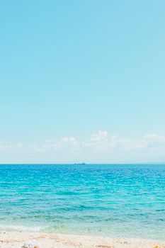 A serene view of a sandy beach and the azure ocean under a clear sky, perfect for relaxation.