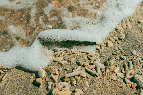 A beach with a white foam on the sand