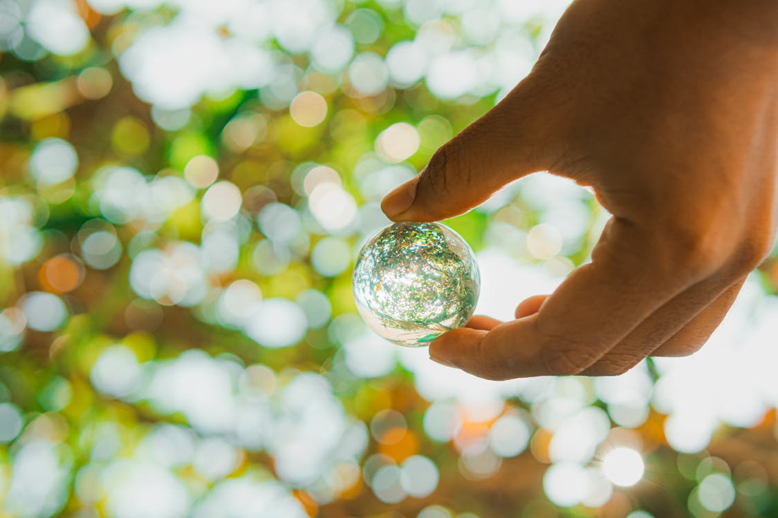 A person holding a glass sphere in their hand