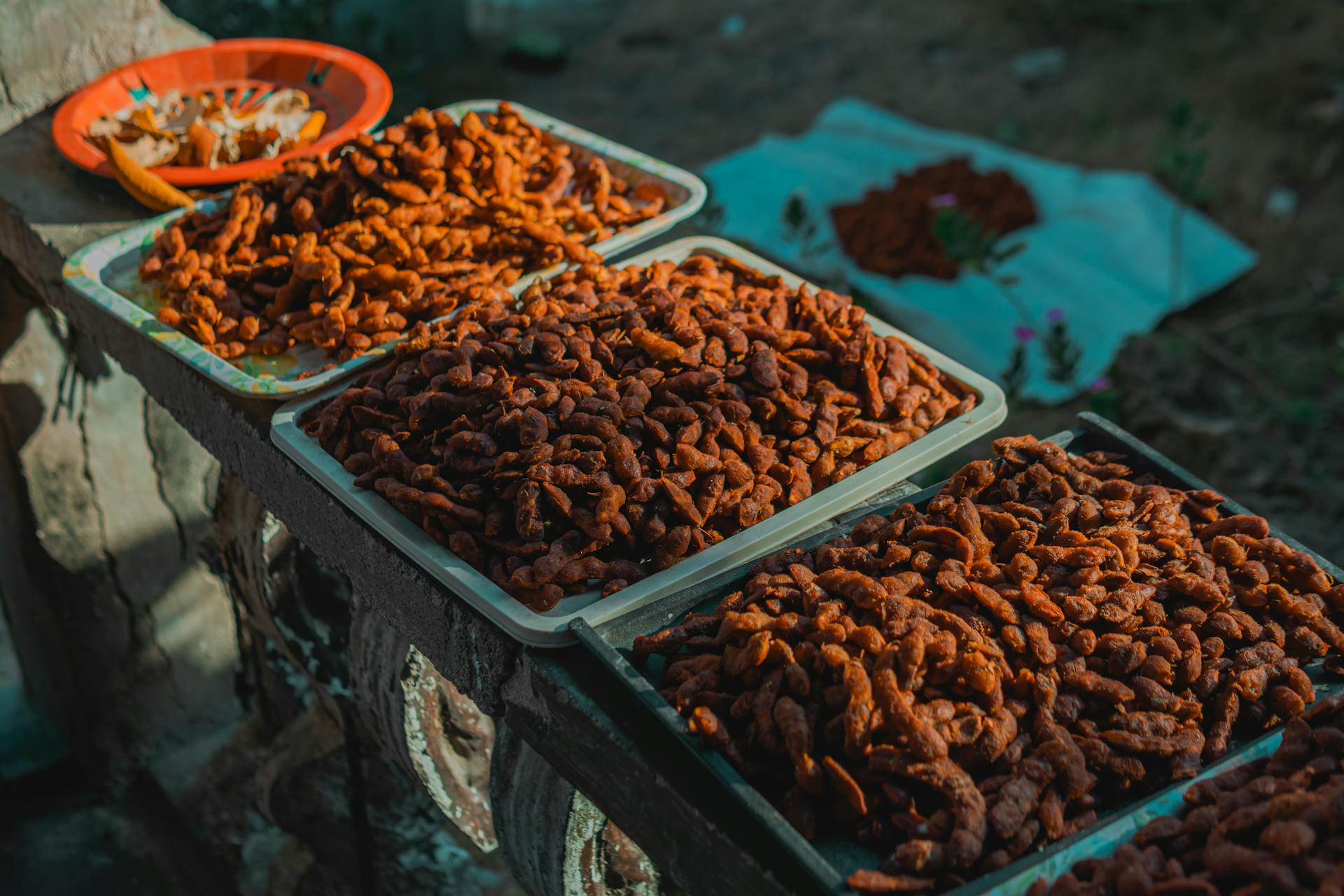 Trays of dried traditional foods basking in the sun outdoors, showcasing culinary culture.
