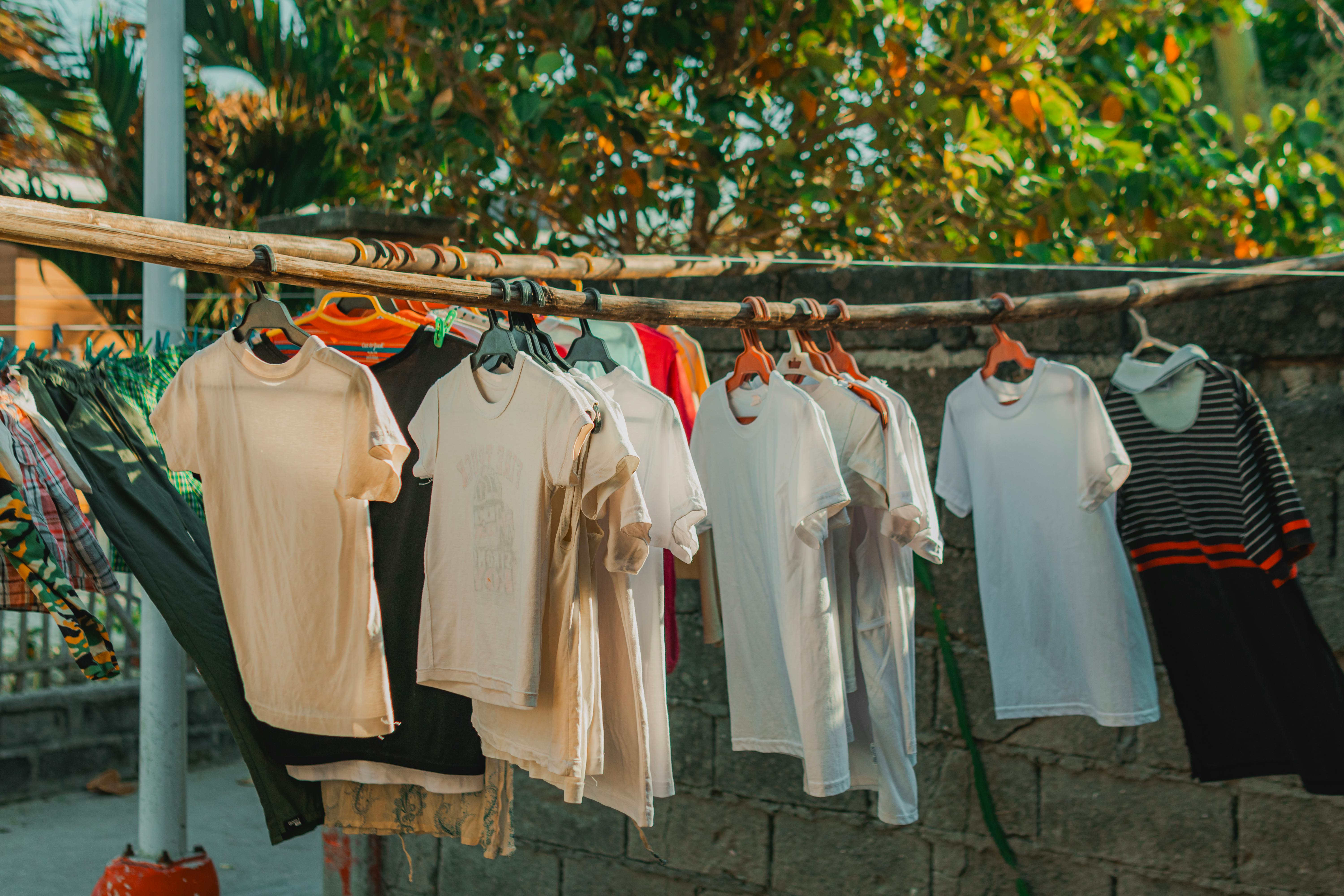 Colorful clothes hanging on an outdoor line in a sunny backyard setting, evoking a fresh and homey atmosphere.