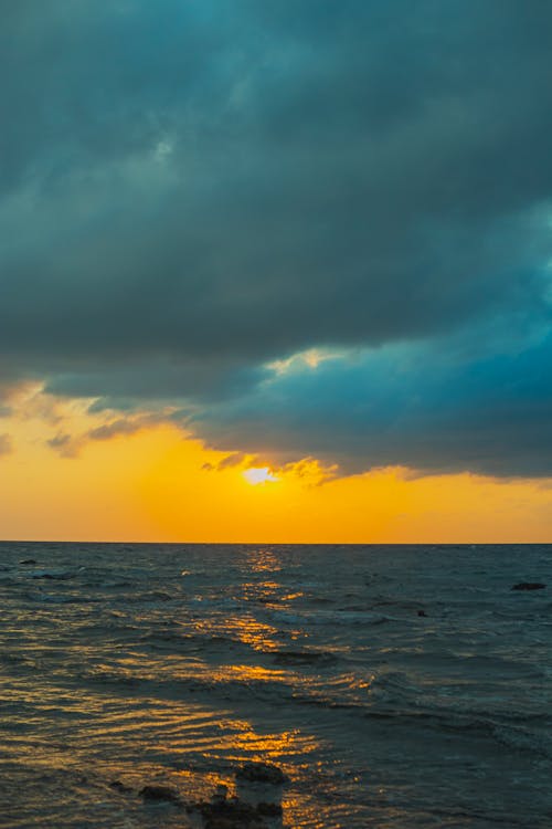 A sunset over the ocean with clouds and water