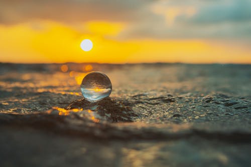 A water ball sits on the beach at sunset