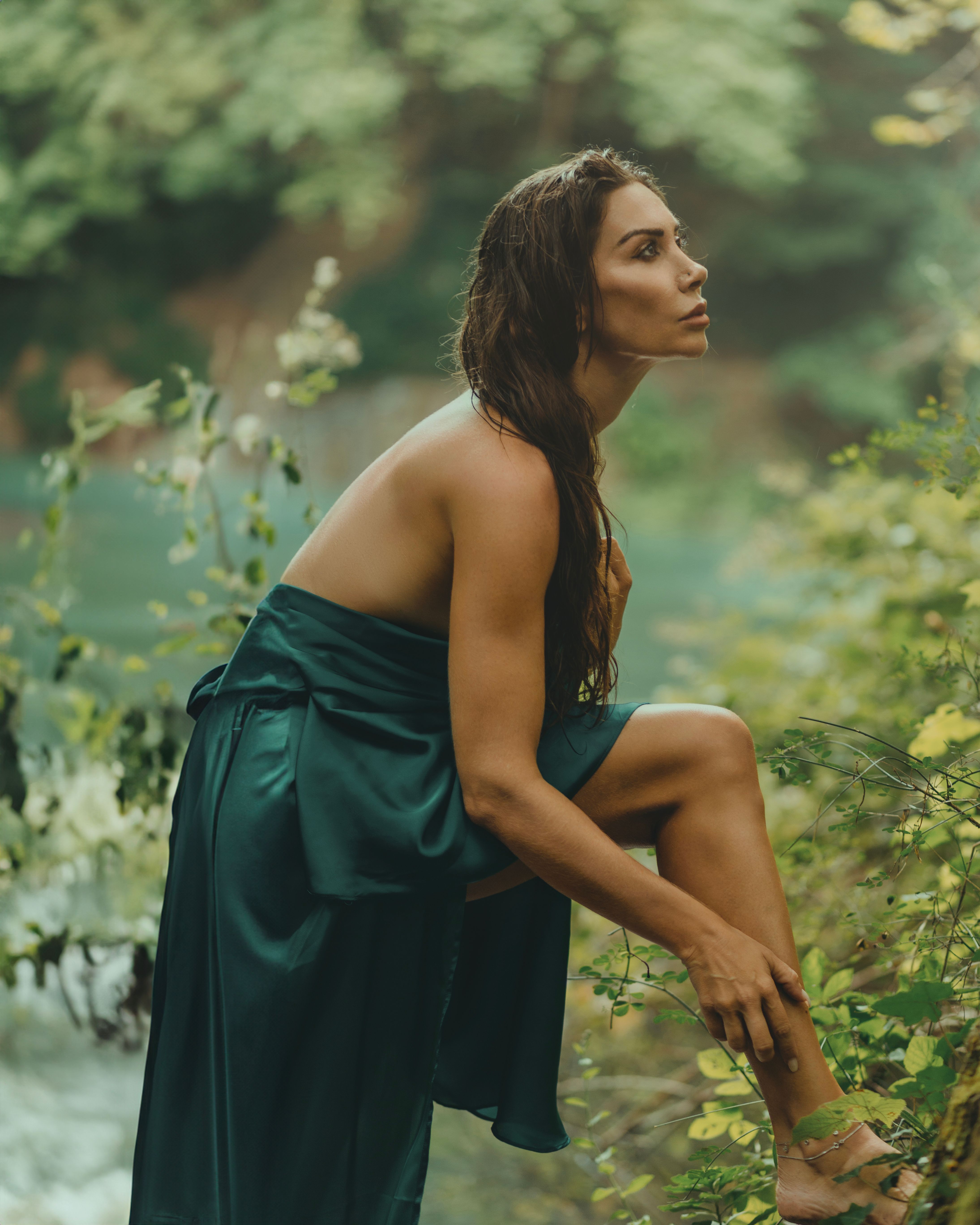 Side View of a Young Woman in a Green Dress Standing in the Bushes near ...