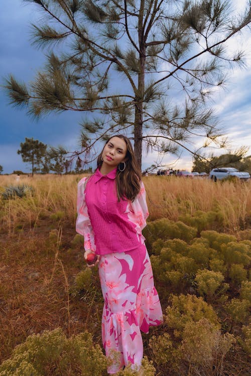 A woman in pink dress standing in tall grass