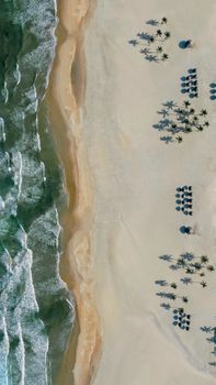Explore the stunning aerial view of a sandy beach in Vietnam with umbrellas and palm trees.