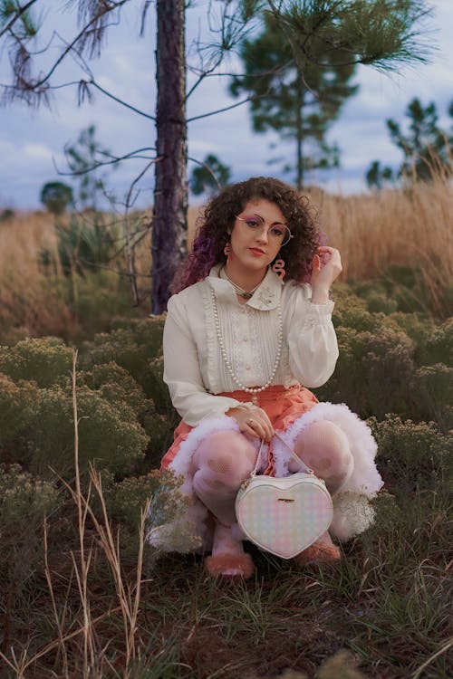 A woman in a skirt and white shirt sitting in the grass