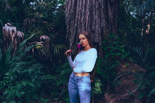 A woman in a white shirt and jeans standing in the woods