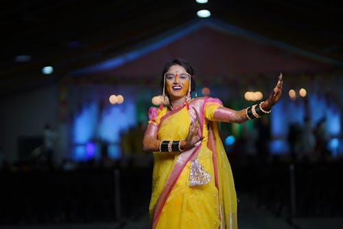 A woman in yellow sari dancing at an event