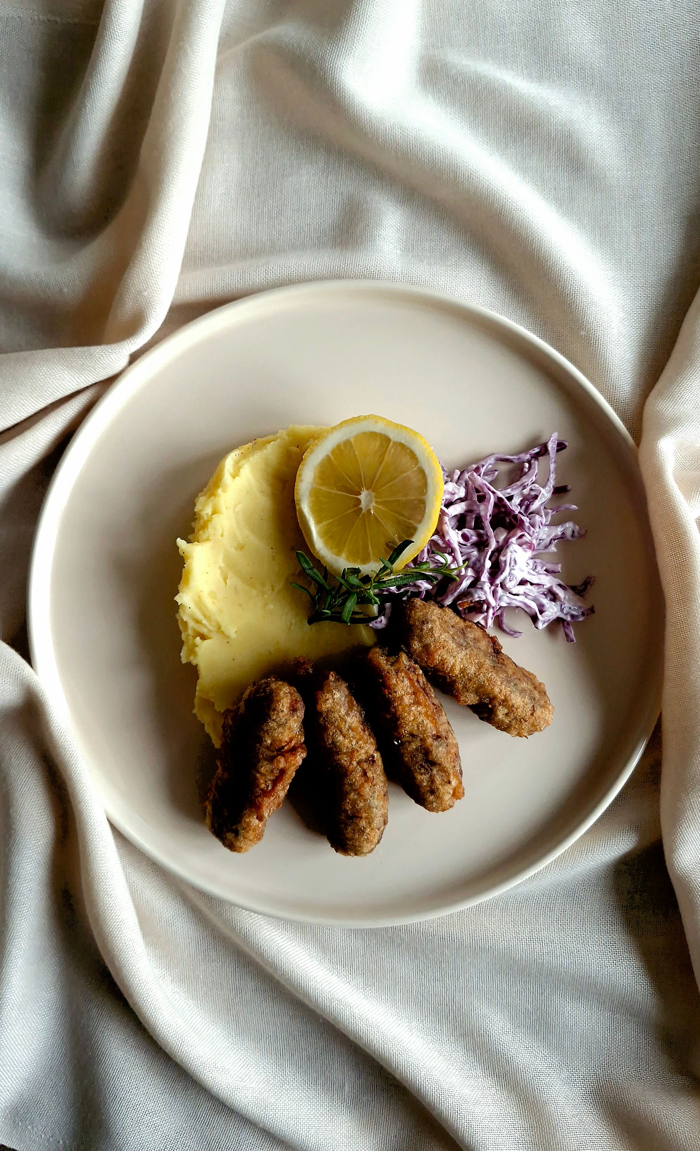 Top view of delicious Turkish kofta served with mashed potatoes and garnished with lemon on a white plate.