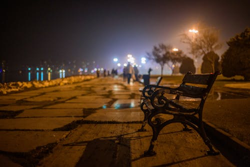 A bench is sitting on the sidewalk at night