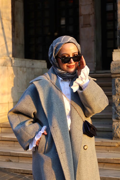 A woman in a grey coat and sunglasses