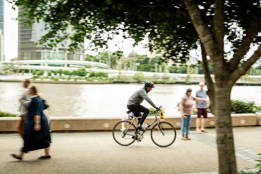 A cyclist rides along the riverside walkway in Brisbane, showcasing city leisure activity.