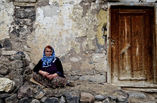 Elderly Lady Sitting in front of a Doorway