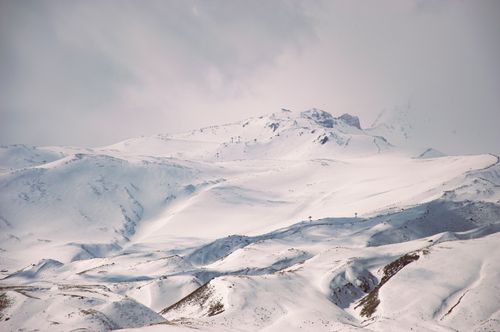 Free Breathtaking view of a snow-covered mountain range under overcast skies, capturing winter's serene beauty. Stock Photo