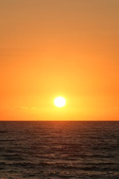 Captivating sunset over the ocean with vibrant orange and yellow hues lighting up the sky.