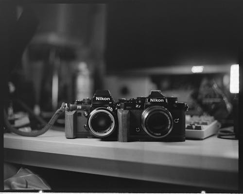 Two cameras sitting on a desk in black and white