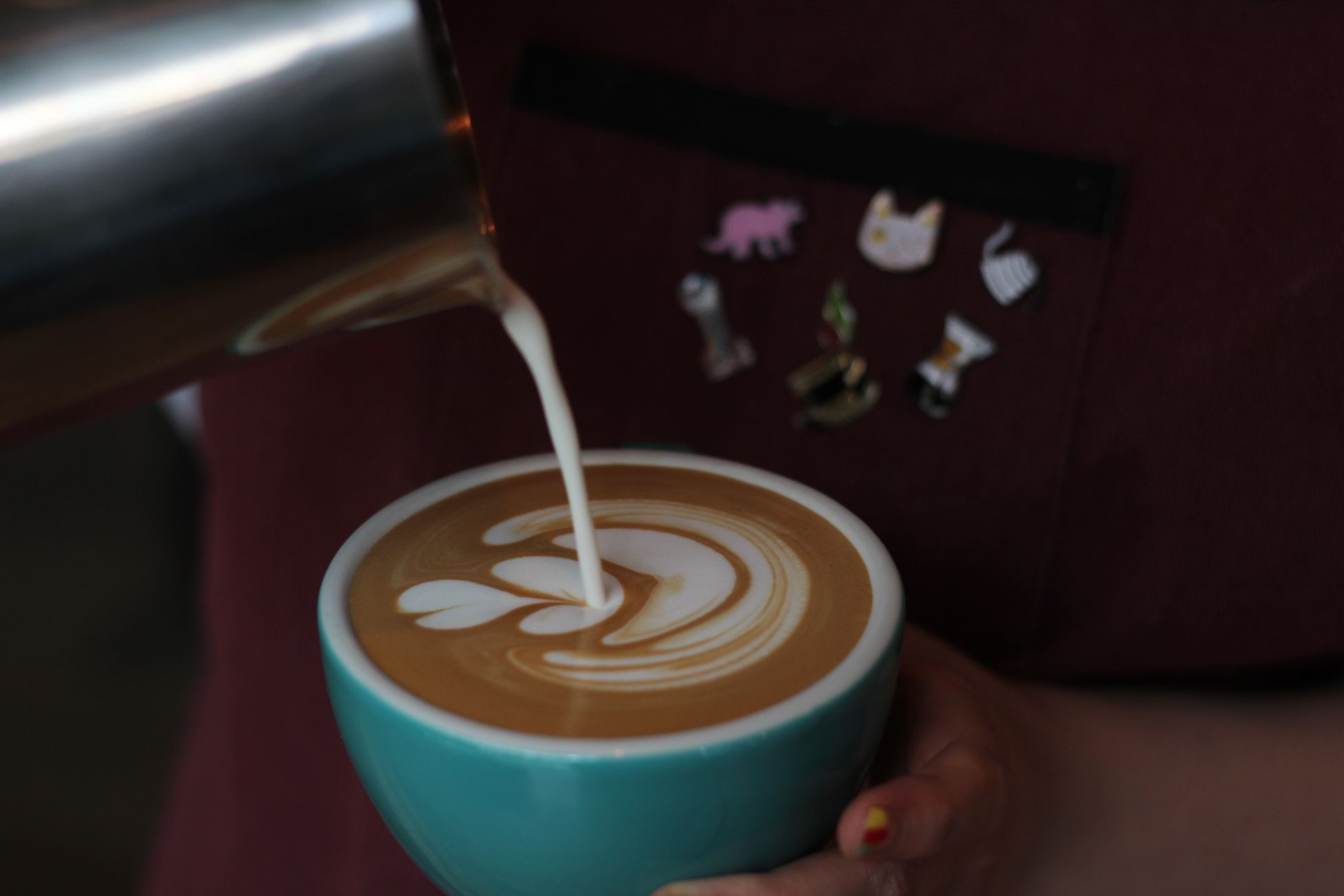Close-up of latte art being poured into a coffee cup, showcasing an artistic heart design.