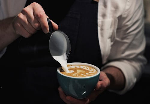 커피에 우유를 붓는 사람의 클로즈업 사진