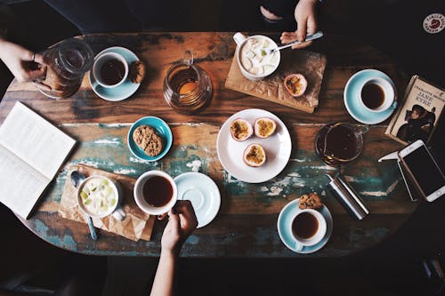 Free Person Sitting Near Table With Teacups and Plates Stock Photo