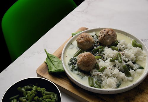 A bowl of soup with meatballs and green beans