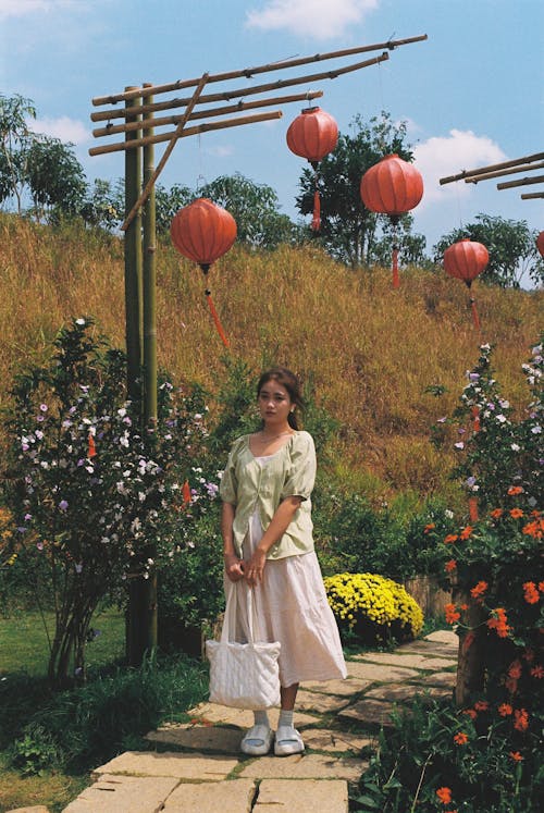 A woman standing in front of a garden with red lanterns