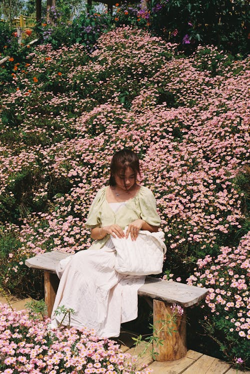 A woman sitting on a bench in a garden
