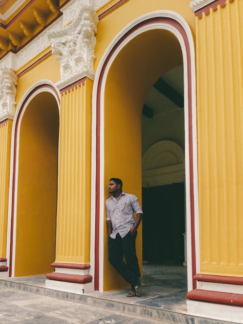 A man standing in front of a yellow building