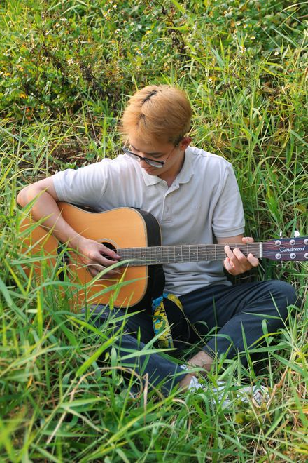 Musician playing an acoustic guitar outdoors — photo by Bùi Hoàng Long on Pexels