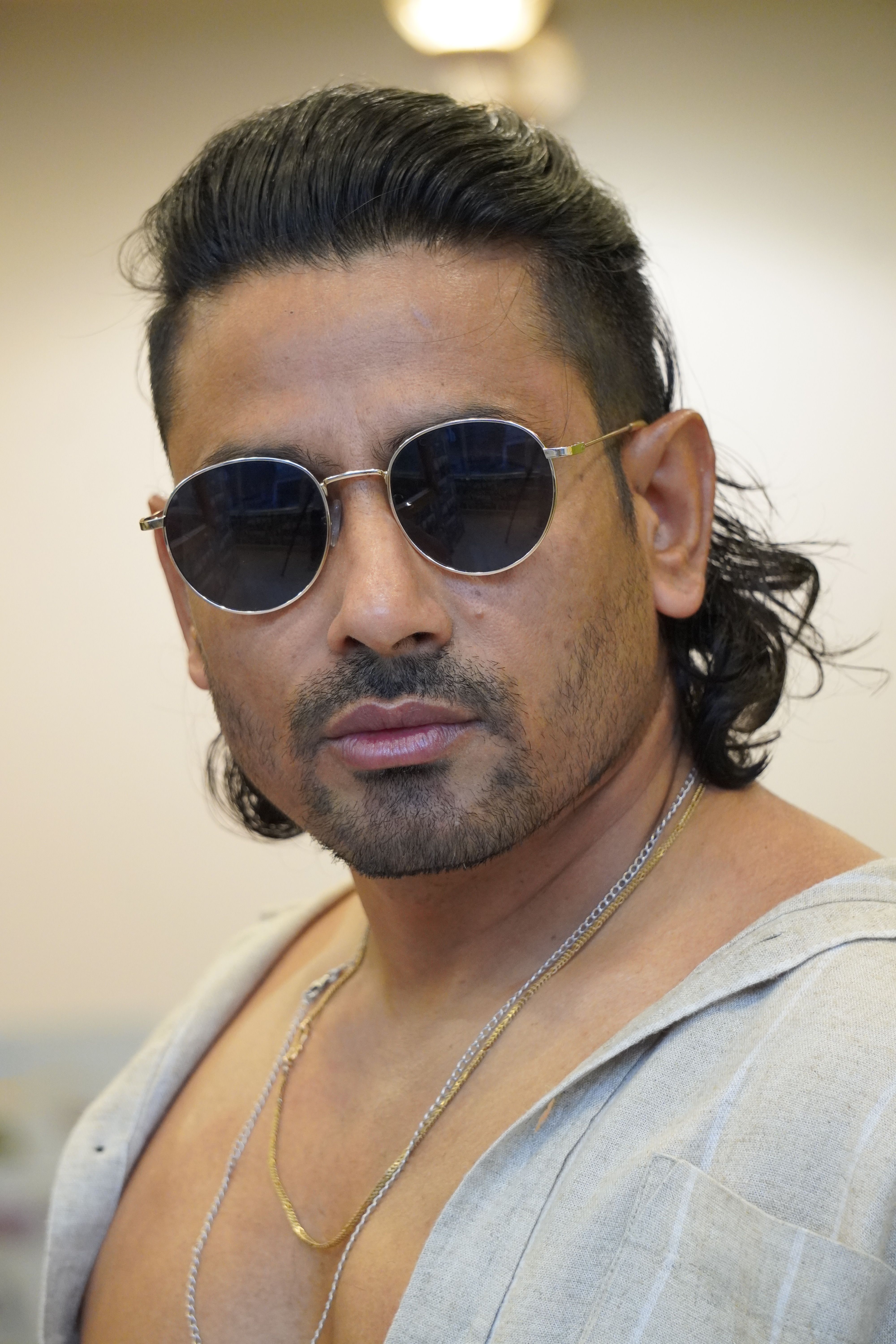Portrait of a confident man wearing sunglasses and an open shirt, exuding style.