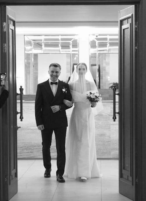 A bride and groom walking out of a door