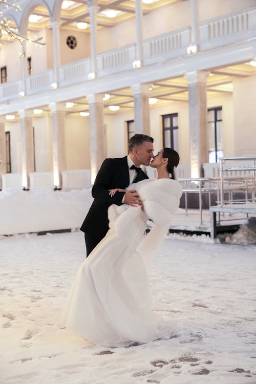A bride and groom kiss in the snow