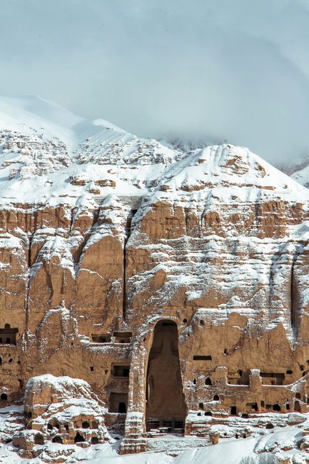 Historic snow-covered Buddha niches in Bamyan, Afghanistan, showcasing ancient rock carvings.