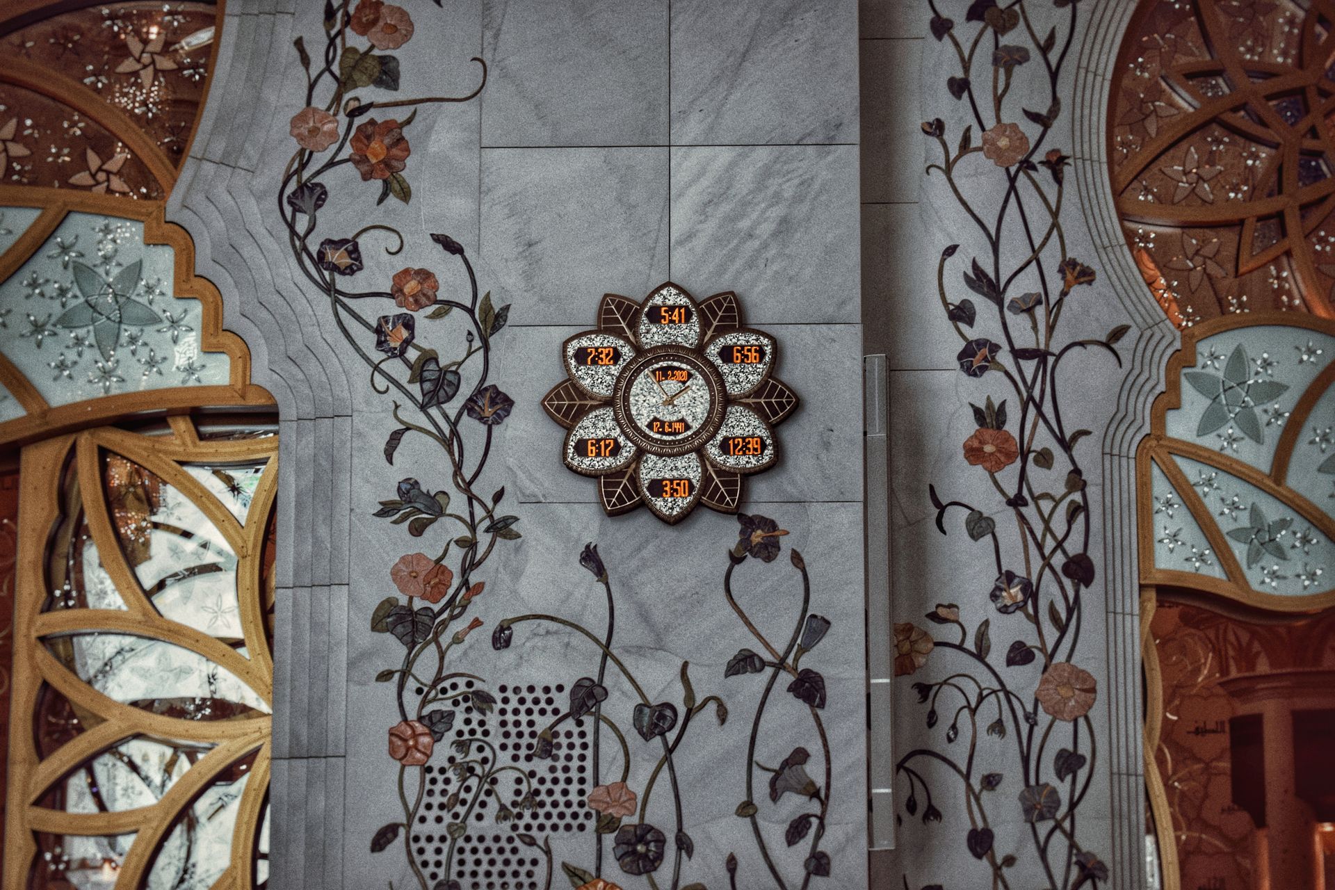 Beautiful wall design with floral patterns and digital clock in an Abu Dhabi mosque.