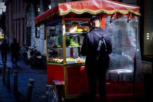 A vibrant street food cart in İstanbul with a man ordering, capturing urban nightlife.