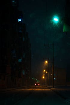 A solitary car on an illuminated street in Mashhad, Iran during a dark, rainy night.