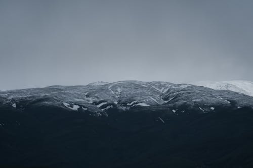 A snowy mountain with a dark sky above it