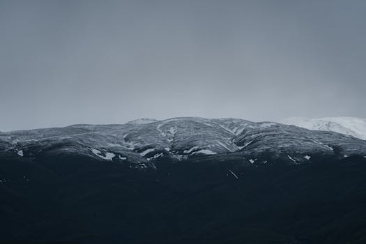 Stunning snow-capped mountains under a cloudy sky in Mashhad, Iran.