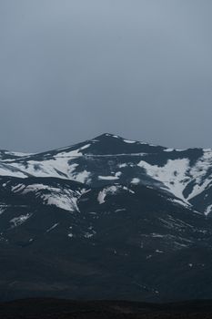 Dramatic snow-covered mountain landscape in Mashhad, Iran, with overcast sky.