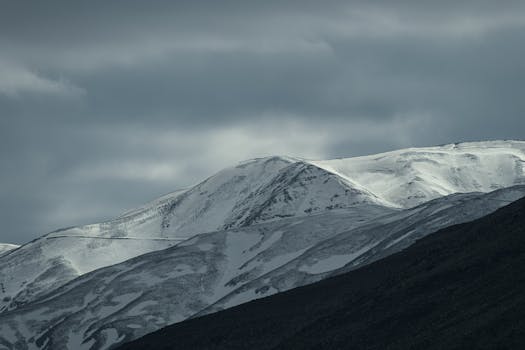 Majestic snow-capped mountains under a moody sky in Razavi Khorasan, Iran.