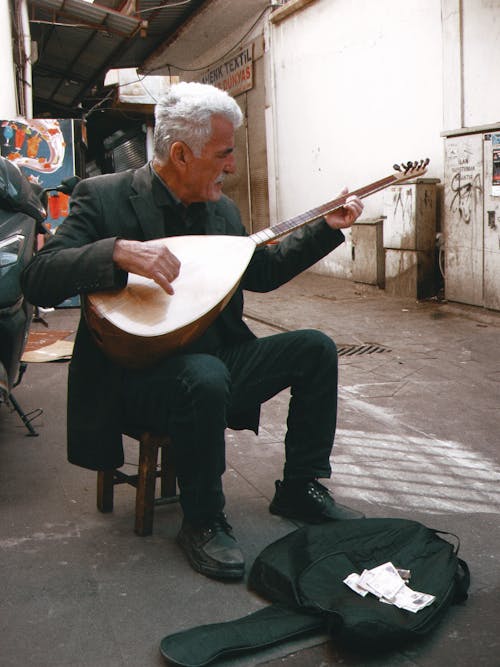 Elderly Man Sitting and Playing Traditional Guitar